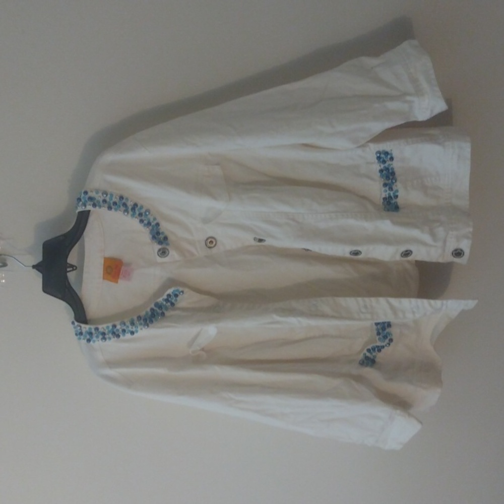 White jean jacket adorned with blue rhinestone like pieces.
